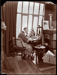 Will R. Barnes in einem Gewand, sitzend an seinem Schreibtisch in seinem Studio, 1903 (Silbergelatineabzug)
